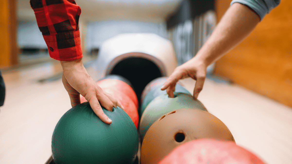 two male players getting bowling balls from a feeder
